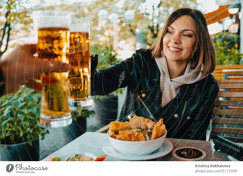 Happy woman clink beer glasses with man in asian cafe in Germany. Positive lady during oktoberfest celebration. alcohol happy young background cheerful face