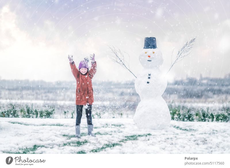Girl cheering with a snowman in the snow sunset frost young purple caucasian lifestyle girl female frosty leisure children hat snowfall wintertime weather