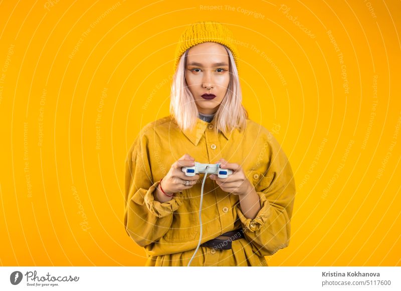Pretty young girl playing video exciting game on Tv with joystick on yellow studio wall. Using modern technology. fun indoor console man leisure woman