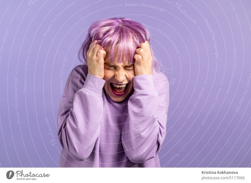 Frightened and screaming woman with dyed purple hair shocked isolated over violet background. Stressed and depressed pretty girl because of bad news. person