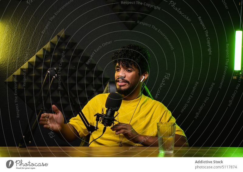 Hispanic podcast host telling story man record smile share dark microphone neon male young hispanic ethnic illuminate influencer speak radio broadcast live