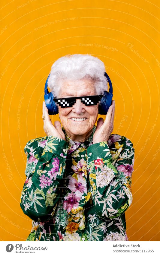Elderly woman in pixel sunglasses listening to music cool smile happy colorful bright female elderly senior aged pensioner retire headphones touch wireless