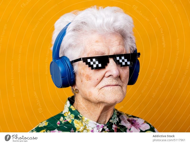 Stylish senior woman listening to music meloman style floral ornament cool bright colorful female elderly aged pensioner retire sound vivid melody headphones