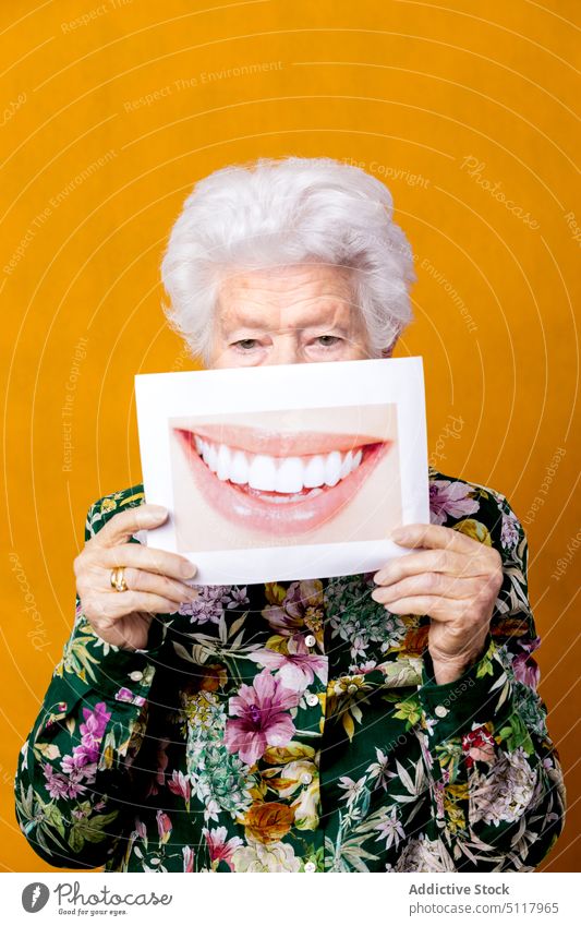Senior woman with photo of smile toothy smile cover face show style dentistry happy colorful bright female elderly senior aged retire wrinkle dental pensioner