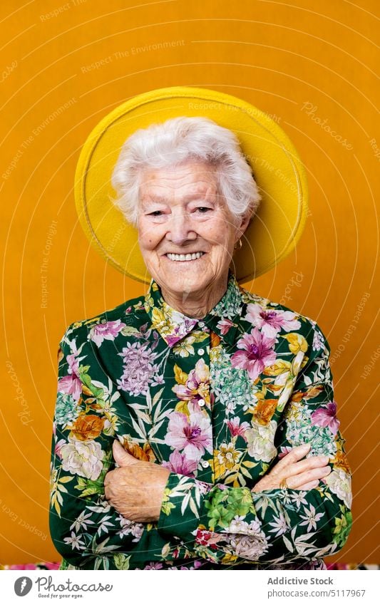 Cheerful elderly female in stylish clothes woman smile positive style appearance shirt hat portrait colorful bright senior aged pensioner retire arms crossed