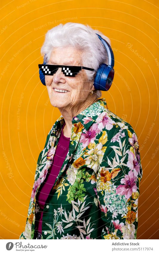 Elderly woman in pixel sunglasses listening to music cool smile happy colorful bright female elderly senior aged pensioner retire headphones wireless headset
