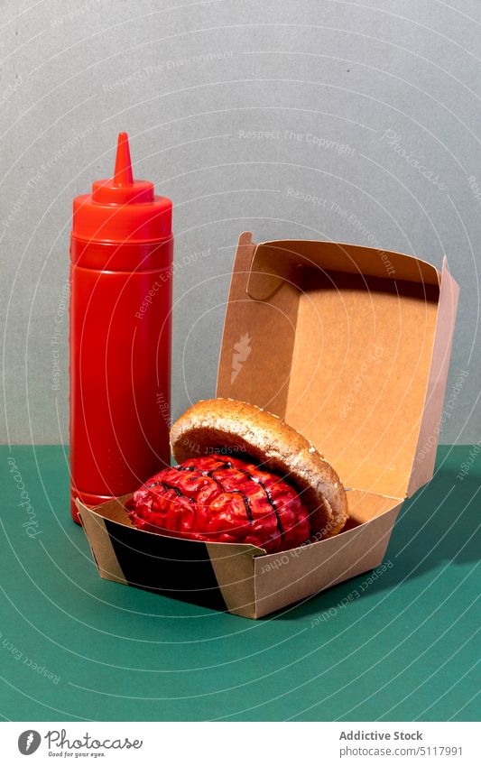 Brain burger in box near ketchup brain bottle concept fast food halloween unhealthy edible serve eco friendly paper plastic calorie junk food lunch sauce