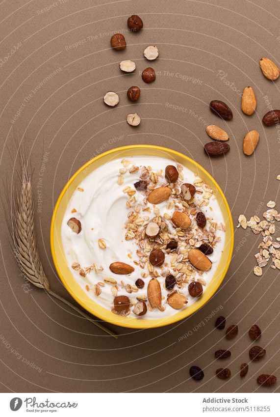 Yoghurt served with oats and dried nuts organic food yoghurt cereals seeds oatmeal raisin morning bowl brown paper texture almonds hazelnuts sweet granola