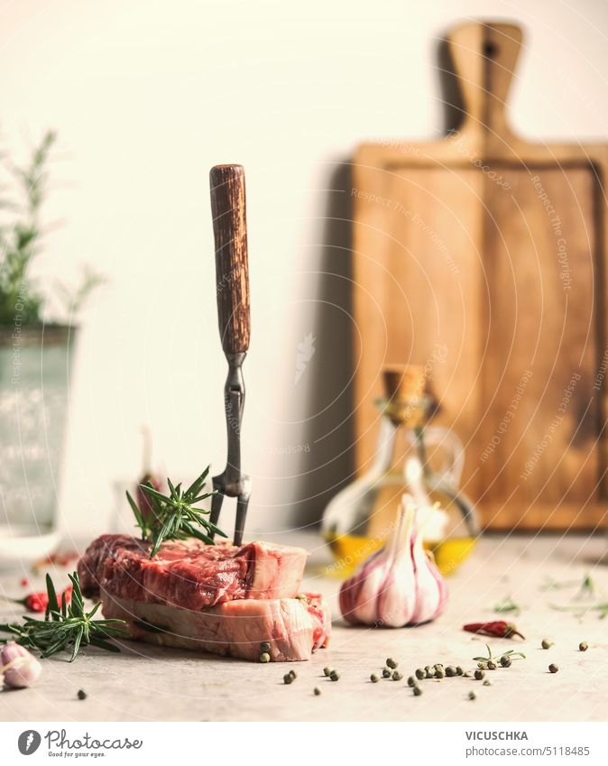 Raw beef steacks with meat fork, herbs and spices on kitchen table, front view raw steaks seasoning garlic angus tenderloin rib eye beefsteak bbq meal fillet