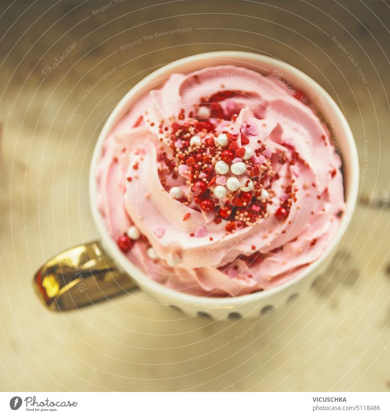 Close up of cup with hot chocolate with pink whipped cream and red sweets. Top view close up top view dessert candy beverage mug drink