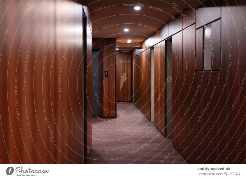 Empty dark interior of the modern Hotel corridor, with wood-paneled walls, elegant carpets and lighting on the ceiling. hotel door empty room floor indoor hall