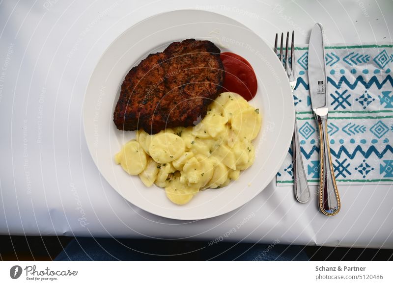 Plate with pot roast, potato salad, ketchup, knife and fork next to it and a patterned napkin paper tablecloth BBQ barbecue evening Festival Nachrung Eating