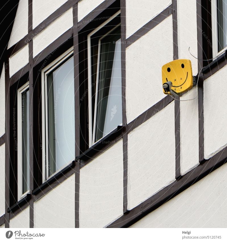 Satellite dish in the form of a yellow smiley on the wall of a half-timbered house Smiley Satellite Dish Antenna Receive House (Residential Structure) Building
