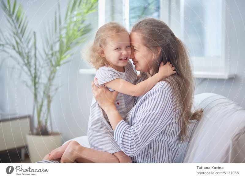 Happy mothers day. Mom and daughter are smiling and hugging on the sofa at home in a bright room. The concept of family happiness with children. Family holiday and togetherness.