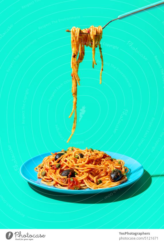Eating italian spaghetti from a plate, isolated on a green background blue bright capers carbs close-up color cooked copy space creative cuisine cut out