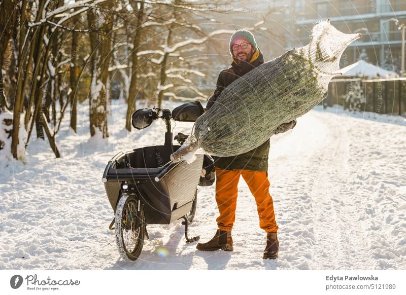 Man transporting Christmas tree on cargo bike sustainable transport ecologic ecology carbon footprint eco friendly cycle ride cyclist biking bicycle