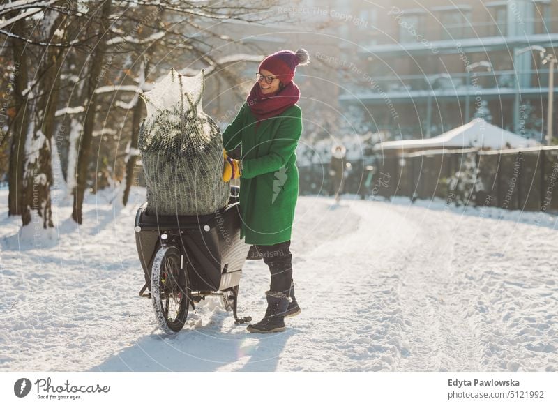 Woman transporting Christmas tree on cargo bike sustainable transport ecologic ecology carbon footprint eco friendly cycle ride cyclist biking bicycle