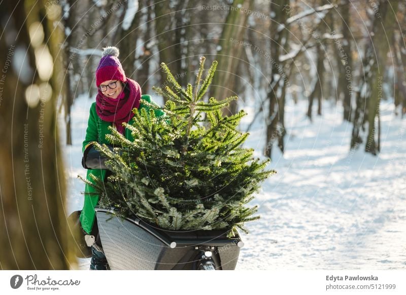 Woman transporting Christmas tree on cargo bike sustainable transport ecologic ecology carbon footprint eco friendly cycle ride cyclist biking bicycle