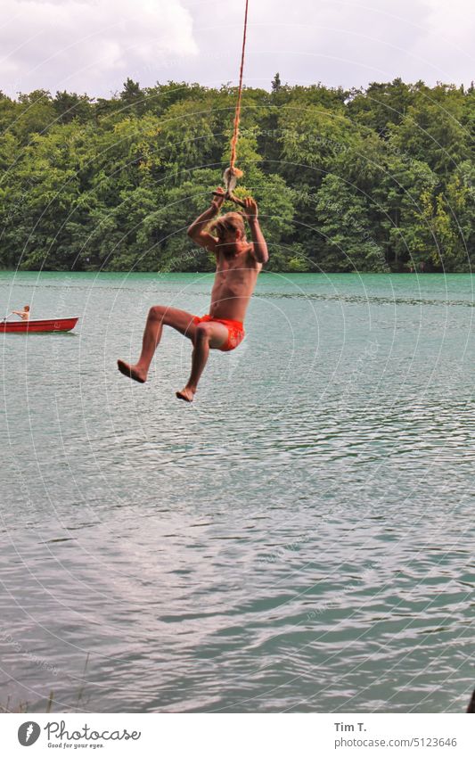 Man swinging on a rope over the lake Lake Summer Brandenburg liepnitzsee Rope Swing Exterior shot Joy Water Colour photo To swing Human being