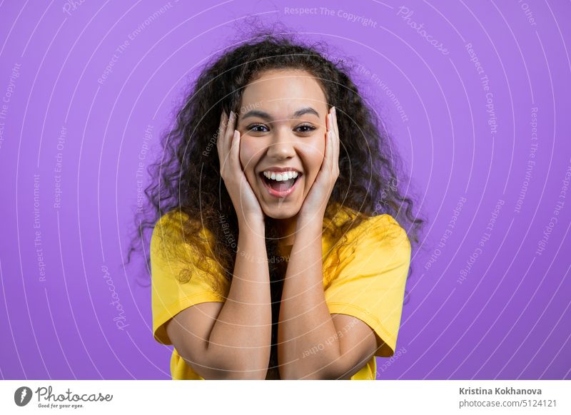 Mixed race woman is very glad, she screaming loud. Concept of sales, profitable offer. Excited happy lady on purple studio background. person young girl win