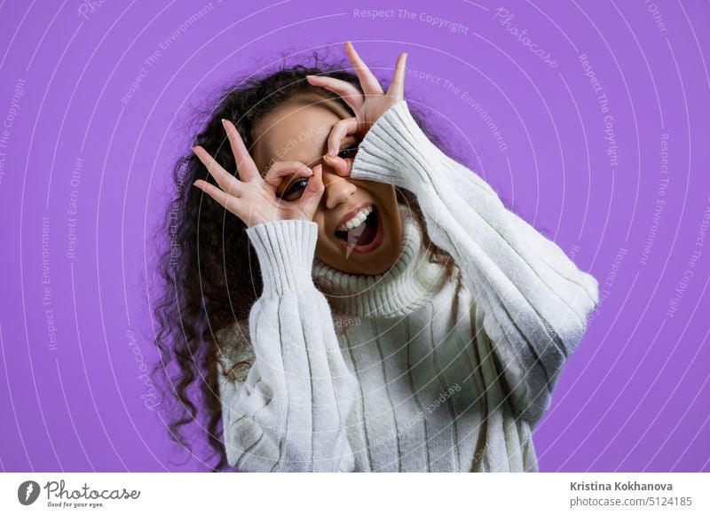 Positive girl making OK sign over eyes like glasses on purple background and smiles to camera. Body language. Young woman. person success positive happy