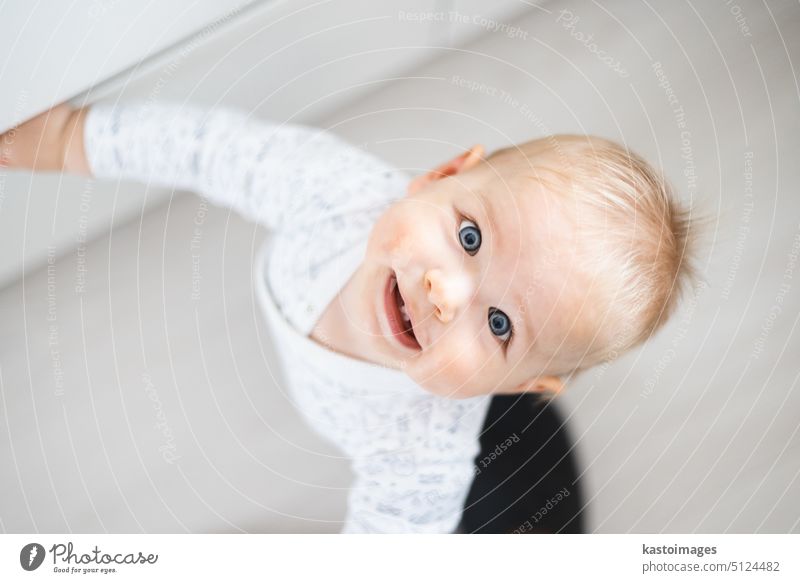 top down view of cheerful baby boy infant taking first steps holding to kitchen drawer at home. Cute baby boy learning to walk little child happy father dad
