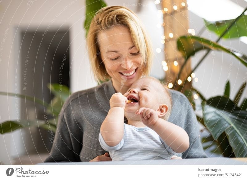 Portrait of young mother cuddling her adorable little child while sitting at the table at home. Sensory stimulation for baby development. family happy cuddle
