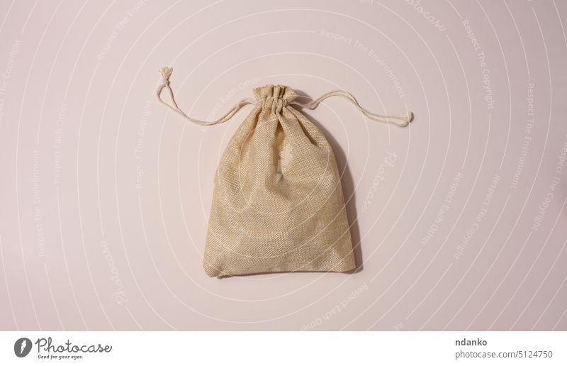 Beige full canvas bag on a beige background, top view package rope sack sackcloth hemp hessian knot linen small studio stuffed textile tied flat blank brown