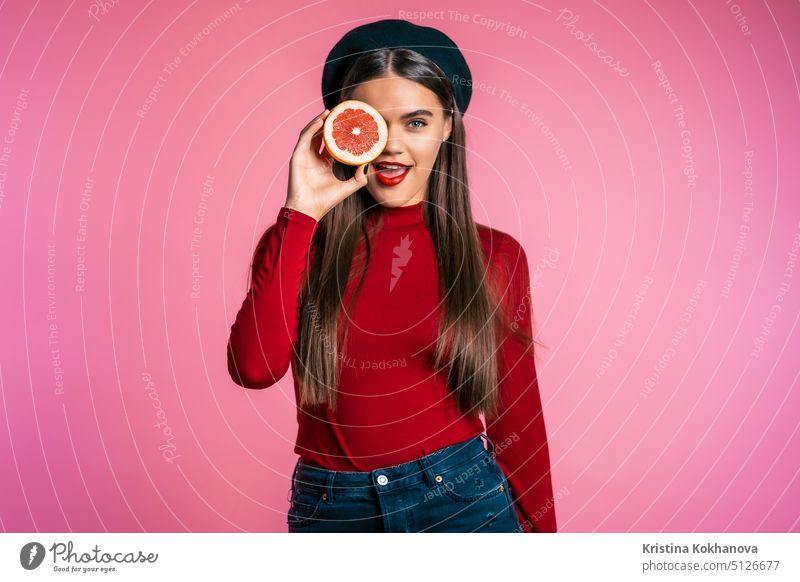 Portrait of young beautiful woman in red with two half of juicy grapefruit pink person citrus diet female isolated background fresh care holding adult detox