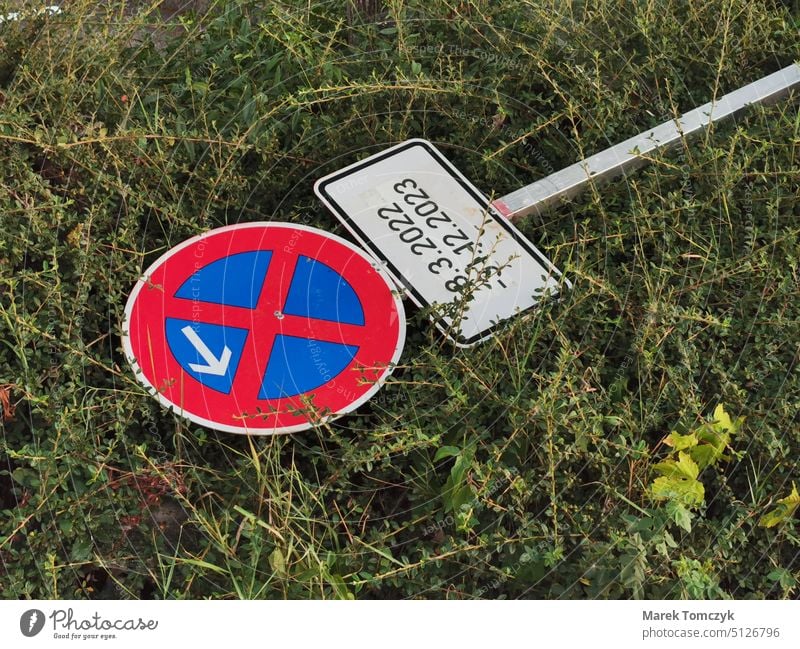 No stopping sign with arrow and additional sign lies in grass no stopping sign No standing Bans Road sign Prohibition sign Signs and labeling Grass Vandalism