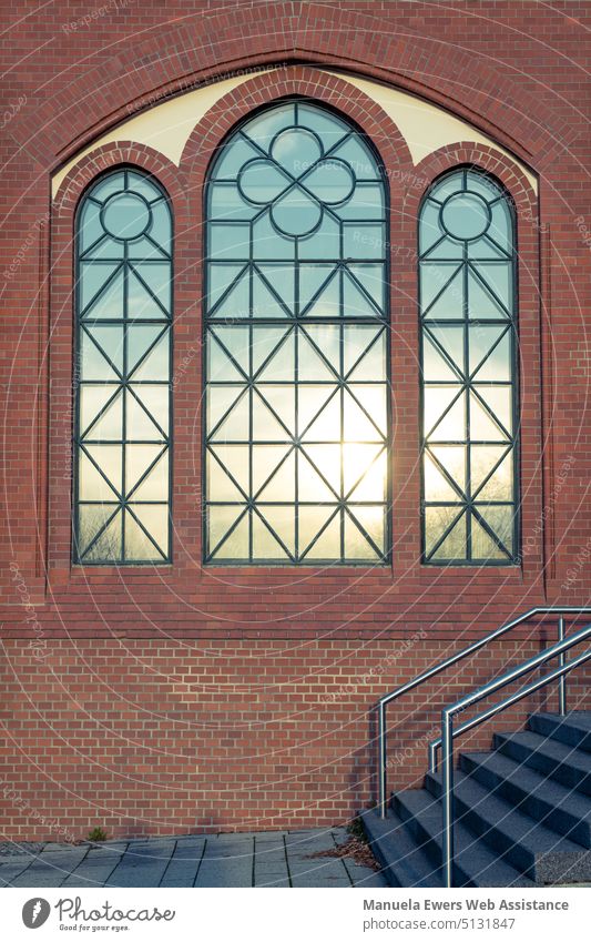 A brick facade with ornate windows that reflect the setting sun. mirror window WindowFacade Ornate Sun Hope Brick wall brick wall Glazed facade Blue sky Stairs