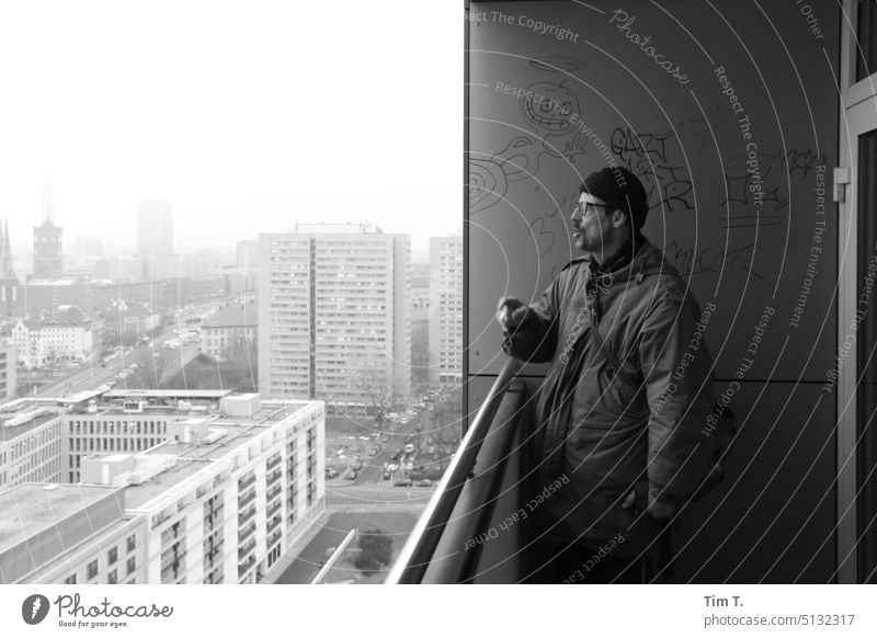 Man with cap talking on balcony with view of Berlin Mitte Balcony outlook b/w Prefab construction Middle Black & white photo Exterior shot Day Architecture Town