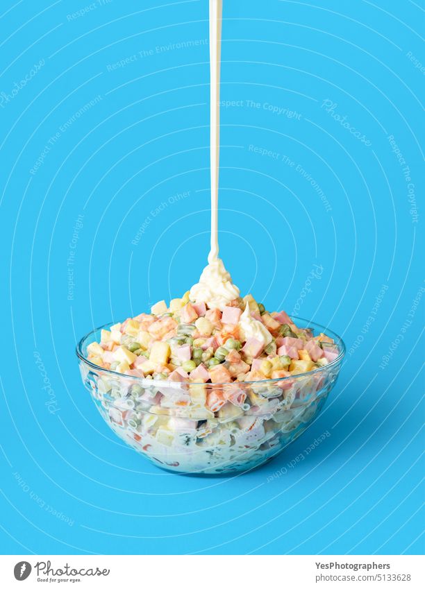 Pouring mayo over oliveir salad, minimalist on a blue background. baked baloney bowl bright carrot chopped christmas close-up cold color cooked copy space