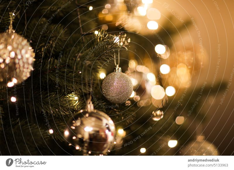 Close up view of beautiful fir branches with shiny golden bauble or ball, xmas ornaments and lights, Christmas holidays background. copy space. Decoration on christmas tree. Festive new 2023 year
