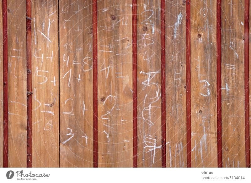 on a wooden wall are written with white chalk numbers and arithmetic problems Wood Wooden wall slats Chalk figures Calculation free time Daub Gimmick