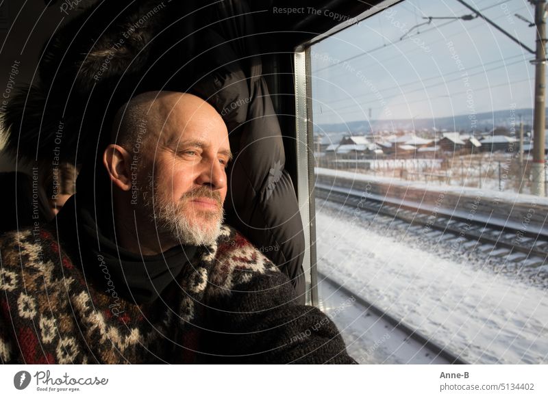 Man sits in knitted sweater on train and looks out window into sunny Siberian winter Track Rail journey train window look out Winter Knitted sweater sympathetic
