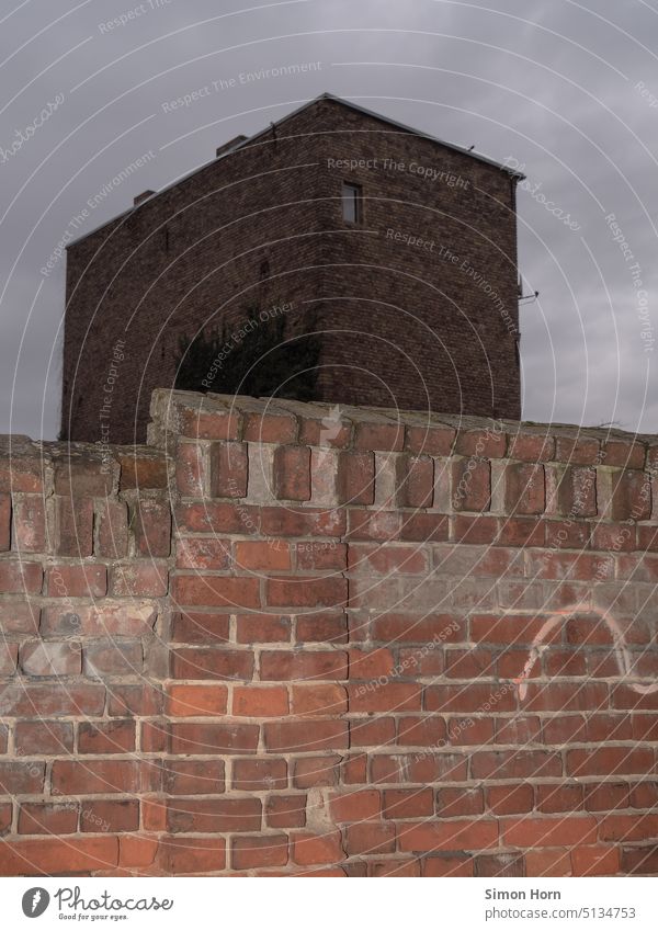 Building behind wall Tower Wall (barrier) Gloomy urban Brick Dark Anonymous Manmade structures cityscape windowless Facade Wall (building) dreariness Container