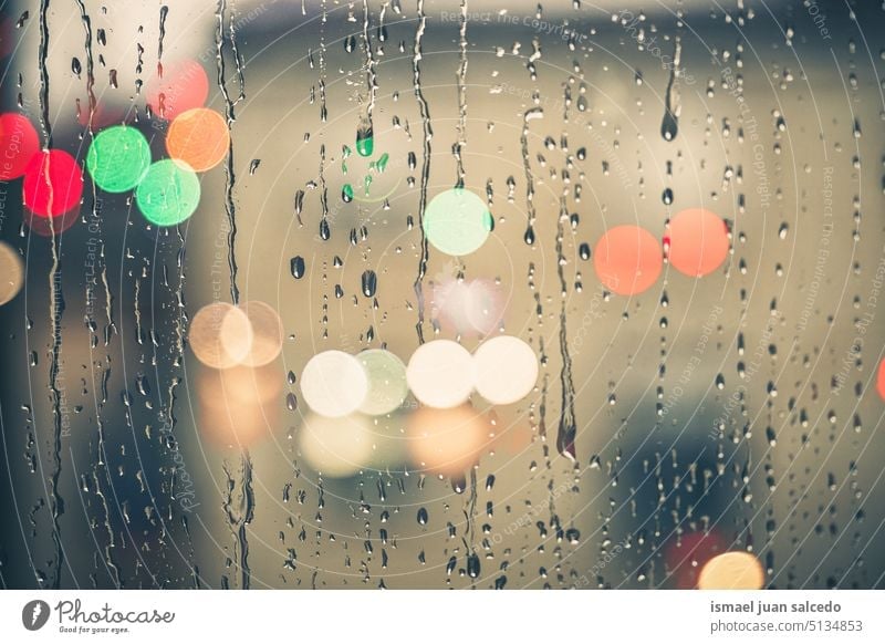 raindrops on the window in rainy days in winter season water wet glass gray grey transparent surface closeup abstract background textured bright splash droplet