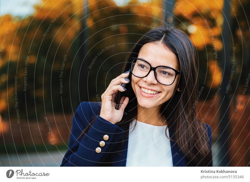 Businesswoman have conversation using mobile phone. Business girl in glasses and formal suit joyfully talks with colleague. Office employee, wage worker, weekdays concept.