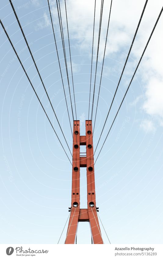 Red iron bridge tower with steel cables. against architectural architecture background blue bridge silhouette building business clouds construction cross design