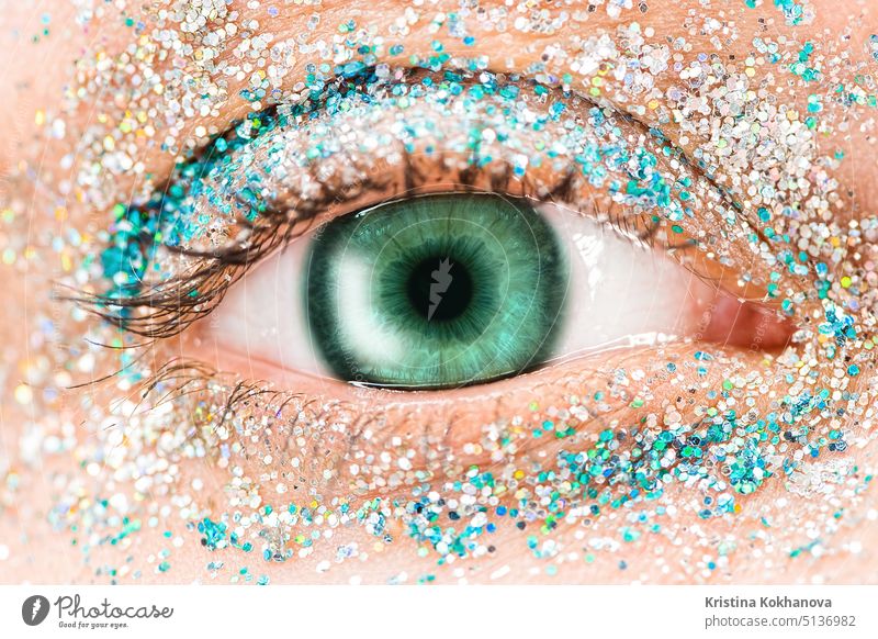 Macro green female eye with glitter eyeshadow, colorful sparks, crystals. Beauty background, fashion glamour makeup concept. Holiday evening make-up detail.