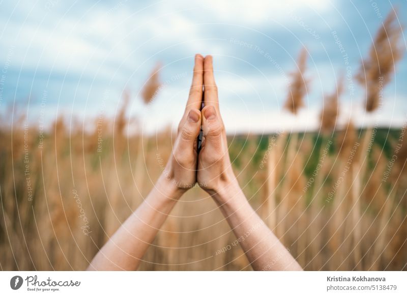 Woman doing namaste yoga mudra on reed natural background. Healthy girl training at summer outdoors. Gratitude, unity with nature, peace and love concept. woman
