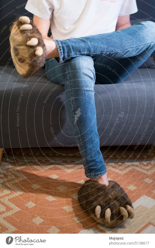 Unrecognizable young person with jeans and bear claws slippers background party shoes carnival costume happy sitting adult style relax concept caucasian room