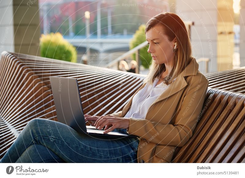 Woman sitting with a laptop on steps outdoors against sunset. woman computer working freelance online bench remote building e learning network lifestyle fun