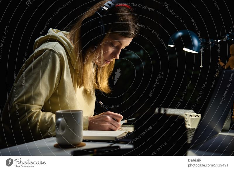 Woman Listening Music In Headphones And Using Laptop At Night woman laptop home night education working homework using casual coffee college communication