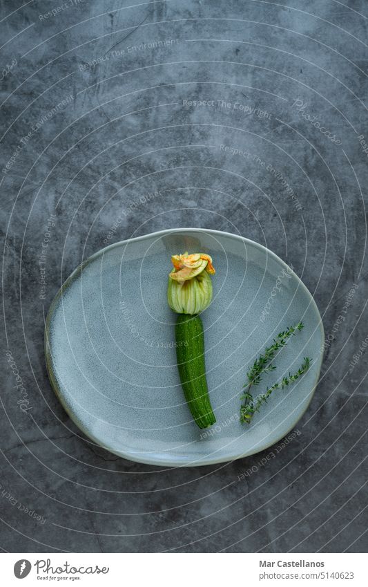 Zucchini flower on plate on stone background. Vertical photo. zucchini vegetable vertical photo top view stone effect courgette green healthy harvest yellow