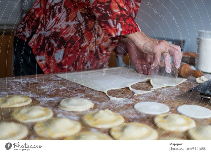 Unrecognizable aged woman cutting puff pastry with a glass to prepare dumplings person appetizer background bowl celebration cooking copy space delicious eating