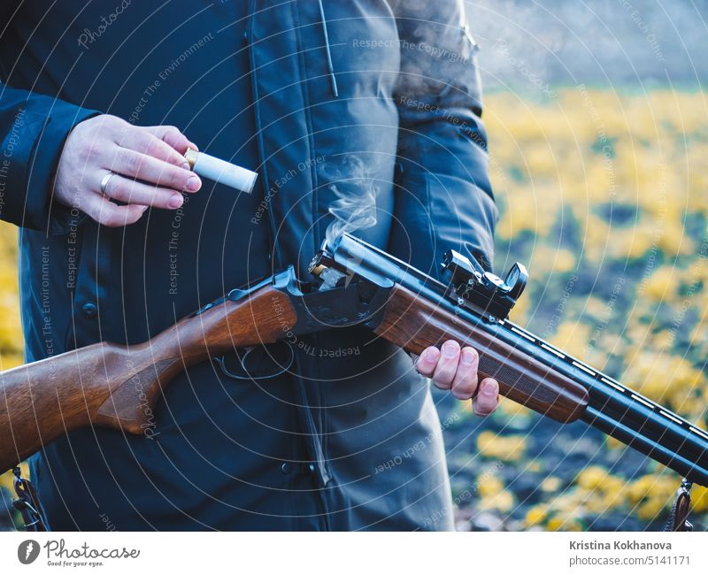 Sports shooting. Hunter reloading cartridge in field. Smoke from the trunks of smooth-bore hunting rifle after firing. 12 activity aim ammunition barrel black