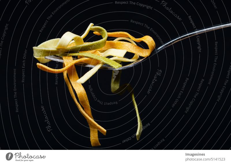 Tagliatelle pasta on a fork isolated on black dark background. Portion of uncooked pasta. Copy room, italian food, carbohydrate nutrition concept. Abstract