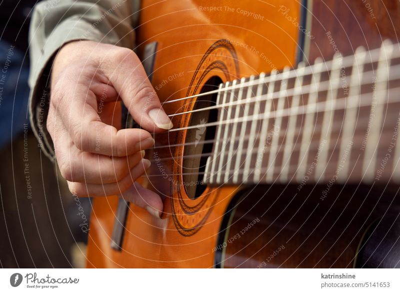 Male hands playing acoustic guitar, close up.  Teacher is giving guitar lesson guitarist fingertips wooden arms strings tab unrecognizable pop-rock fingers